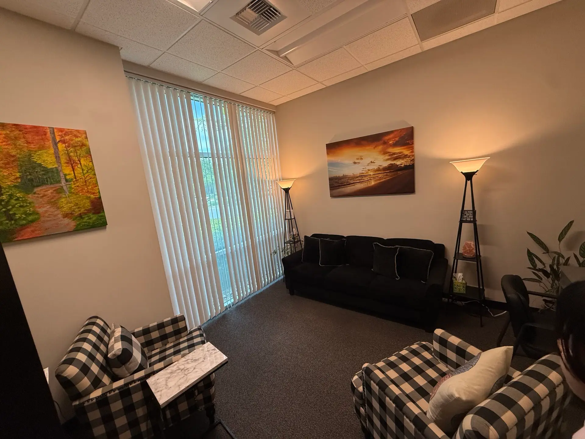 A counseling office with buffalo-check chairs and a sunset painting.