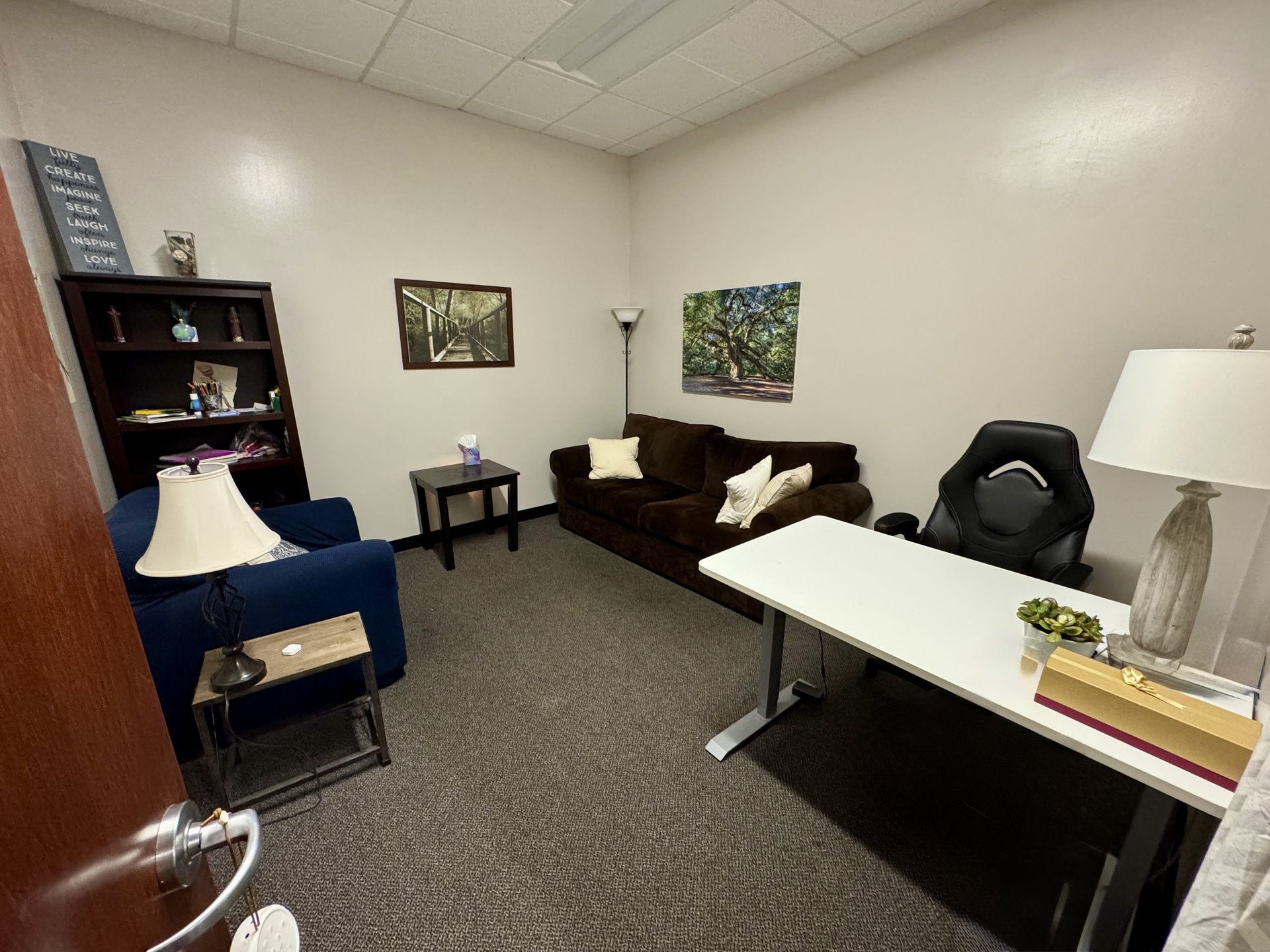 Office #10: brown sofa, blue armchair, bookshelf, and a white standing desk.